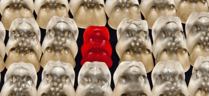 Ein rotes Gummibärchen innerhalb vieler weißer Gummibärchen